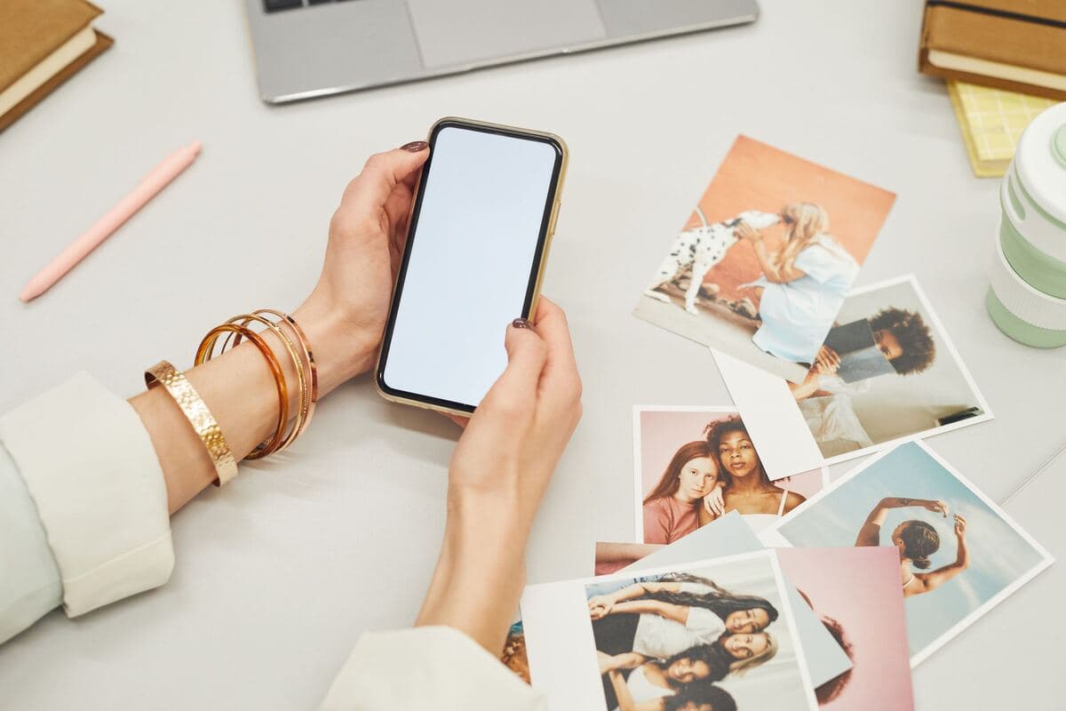 Duar që mbajnë telefonin mbi fotografi të printuara